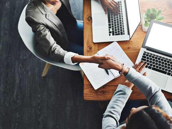 image of shaking hands near laptops